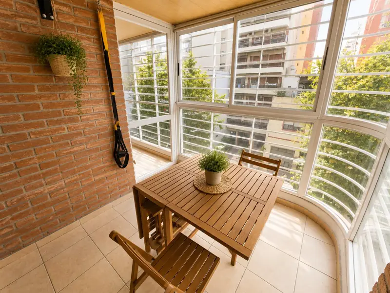Balcón terraza con mesa y ventanal curvo